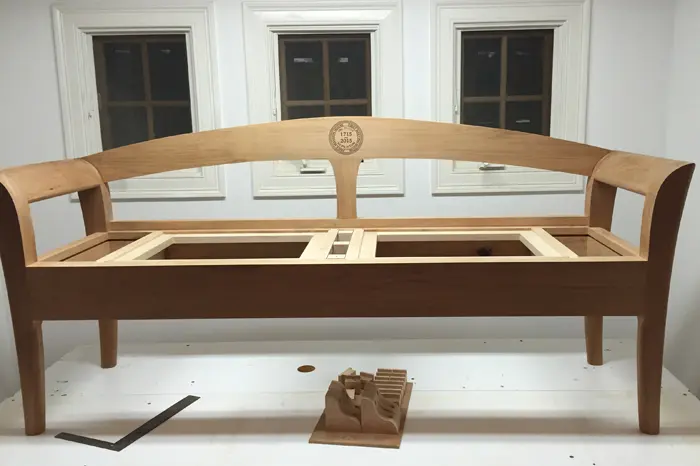 Wooden bench frame in front of windows.