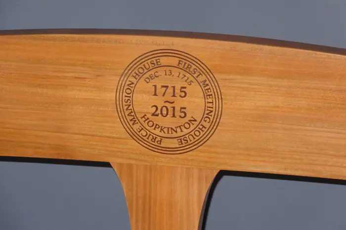 Wooden chair back with engraved emblem.