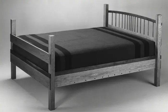 Wooden bed with striped blanket.