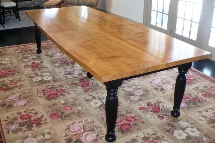 Wooden dining table on floral patterned rug.