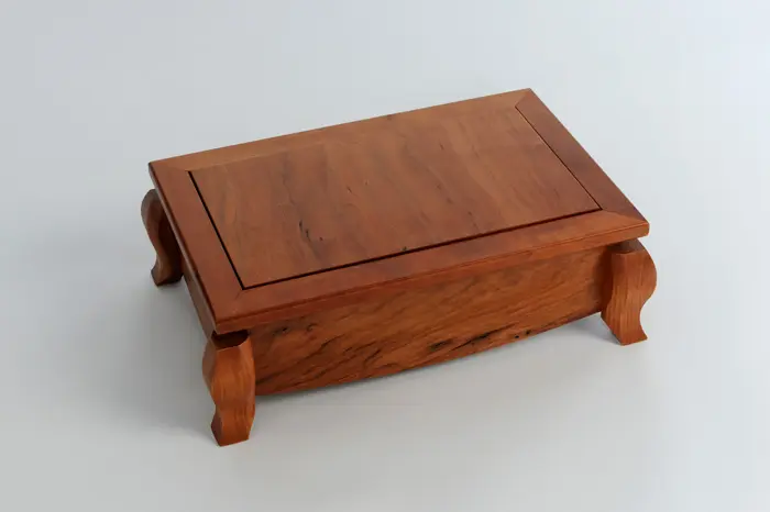 Wooden box with decorative curved legs.