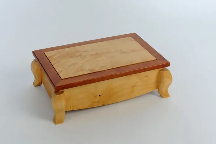 Wooden box with decorative curved legs.