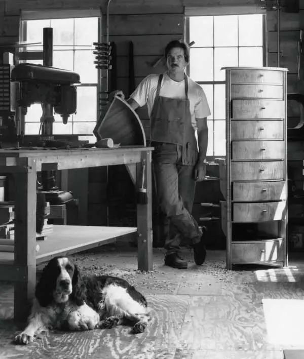 Woodworker with dog in workshop, black-and-white.