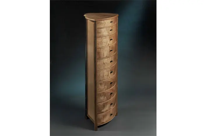 Tall wooden chest with multiple curved drawers.