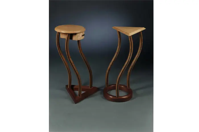 Two artistic, curvy wooden stools displayed.