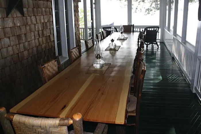 Long wooden dining table on porch.