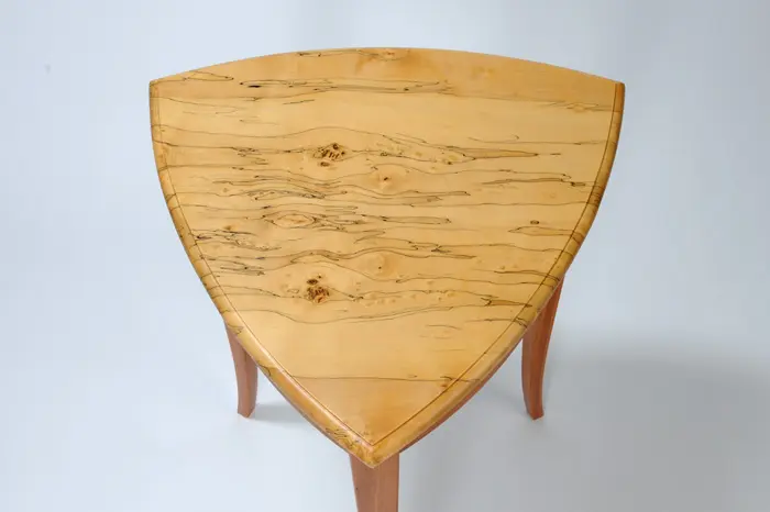 Triangular wooden table with distinctive grain pattern.
