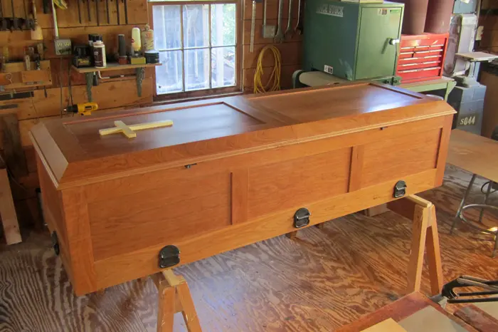 Wooden coffin on sawhorses in workshop.